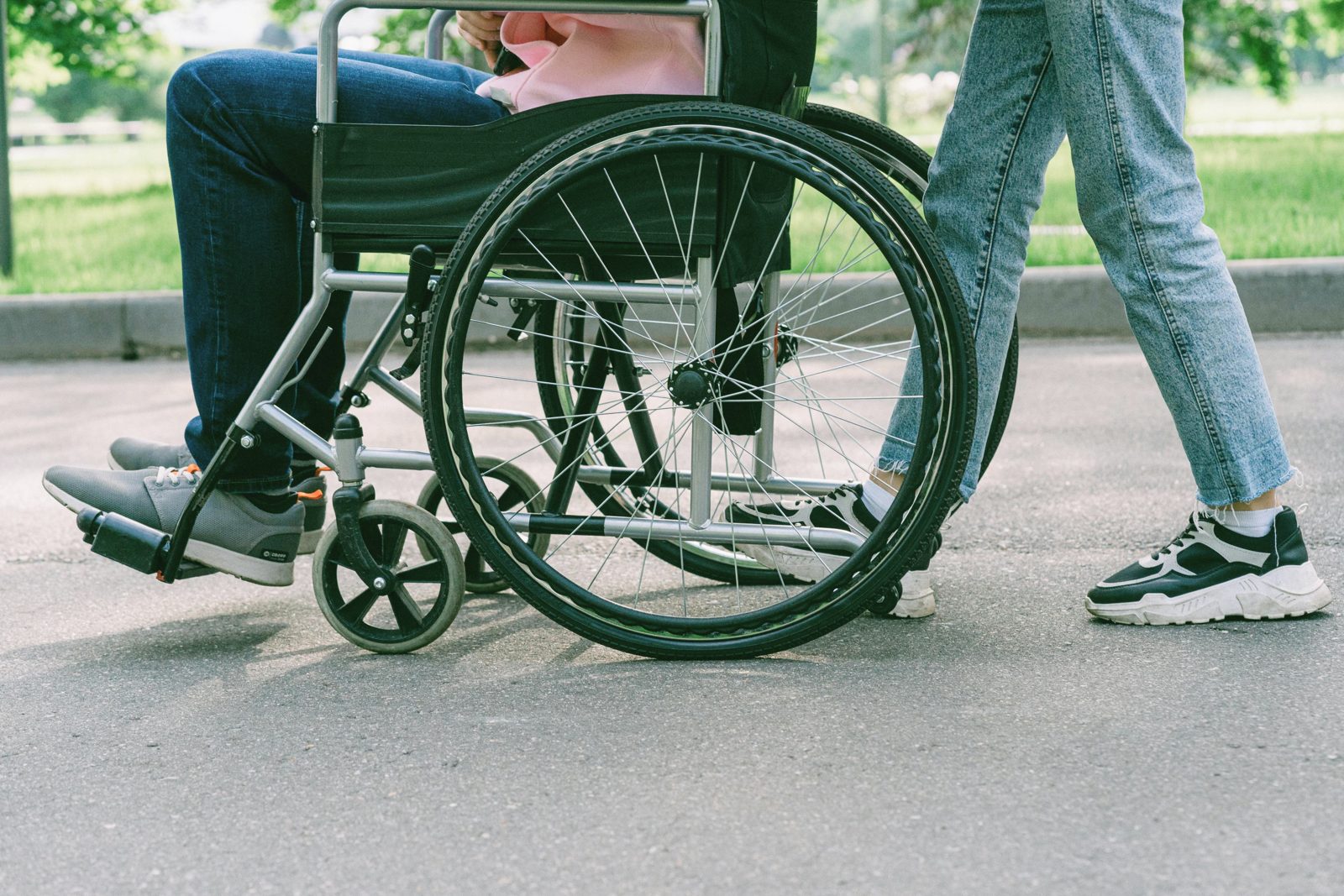 A person in a wheelchair being accompanied on a walk